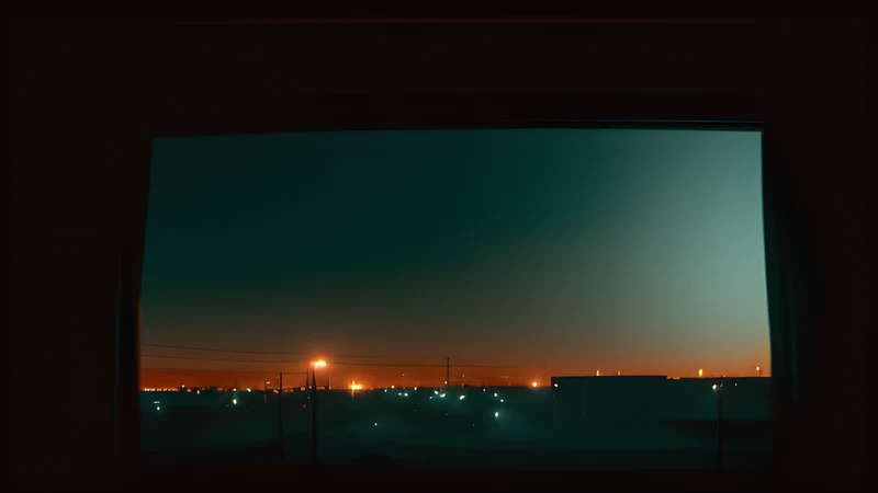 An Arctic town under midnight sun seen through half-closed window blinds