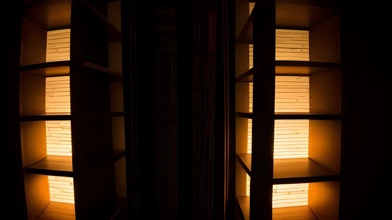Two towering bookshelves of glowing spines facing each other across a dark room