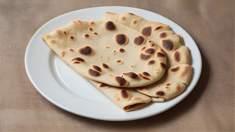 Stack of golden, flaky Kenyan chapatis on a wooden board with visible layers at the torn edge